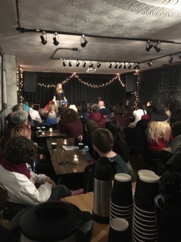 A group of people are sitting at tables in front of a stage