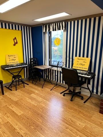 A room with two keyboards and a chair in it.