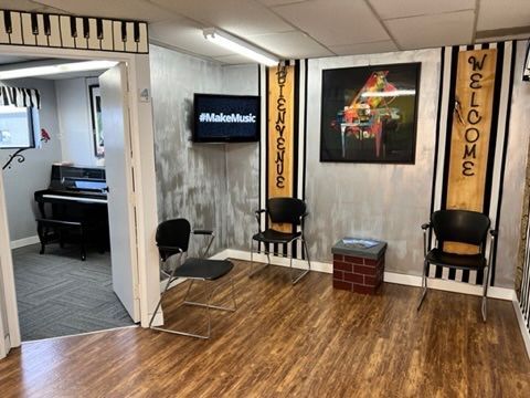 A waiting room with chairs , a piano and a television.