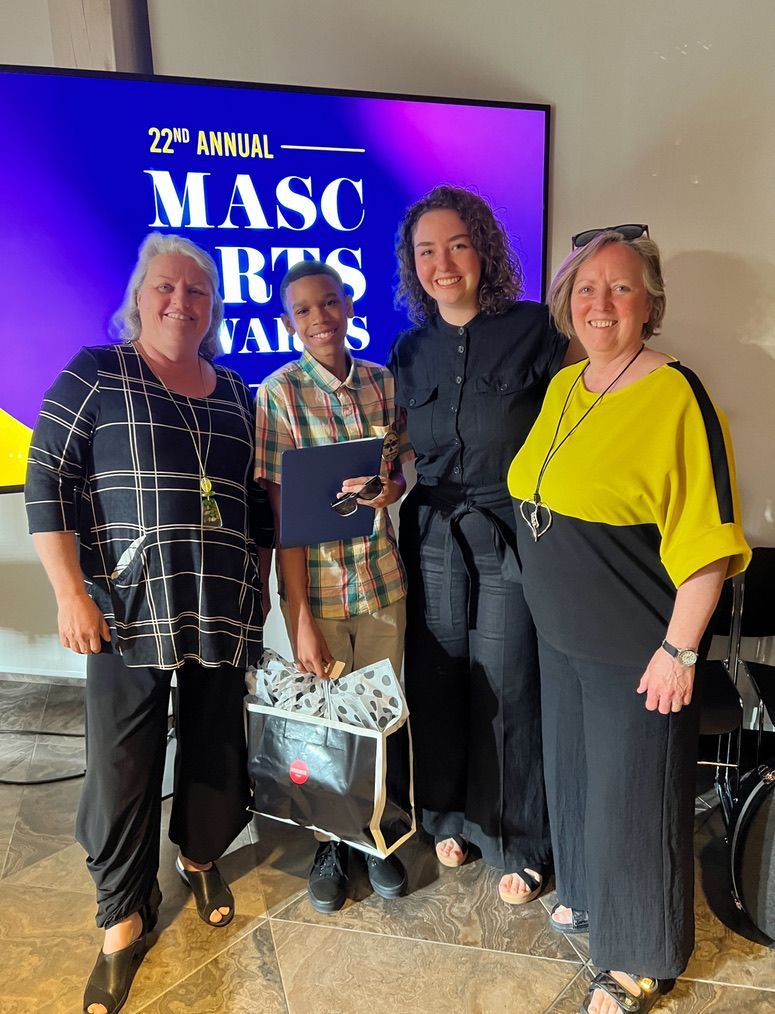 A group of people are posing for a picture in front of a screen that says masc arts awards.