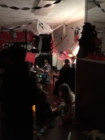 A group of people are gathered in a dark room decorated for halloween