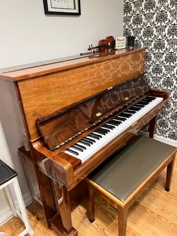 A piano is sitting in a room next to a bench.
