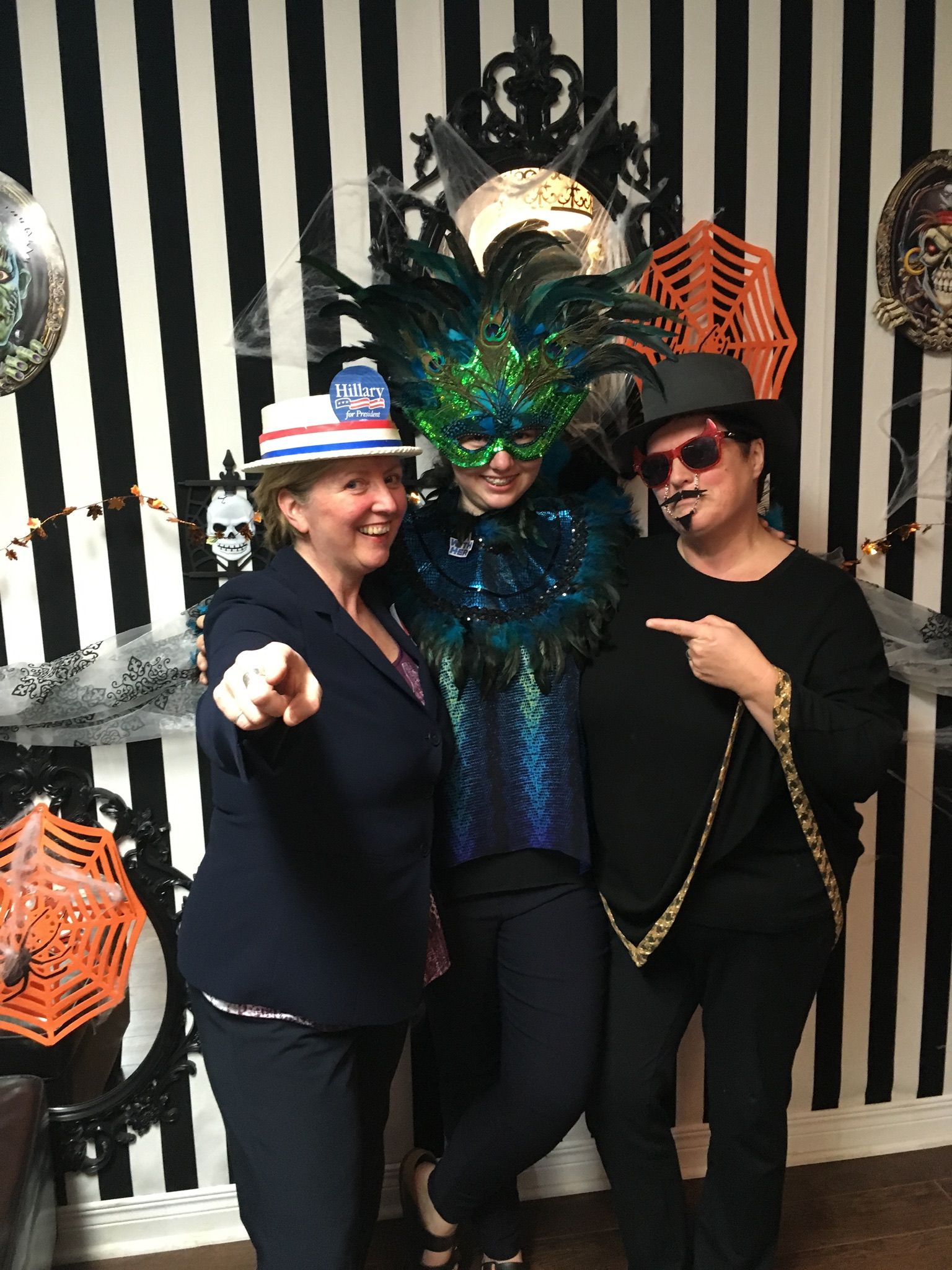 Three people are posing for a picture in front of a striped wall.