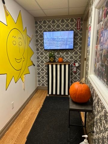 A hallway with a yellow sun on the wall and a pumpkin on a table.