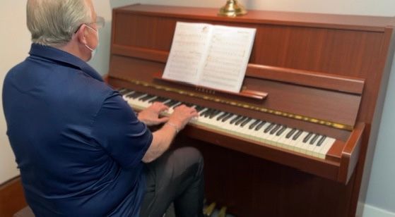 A man wearing a mask is playing a piano.