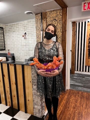 A woman wearing a mask is holding a stuffed animal in a room.