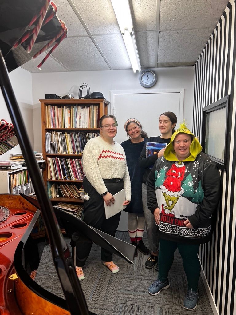 A group of women are standing in a room with a clock on the wall.