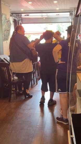 A group of people standing in a restaurant talking to each other