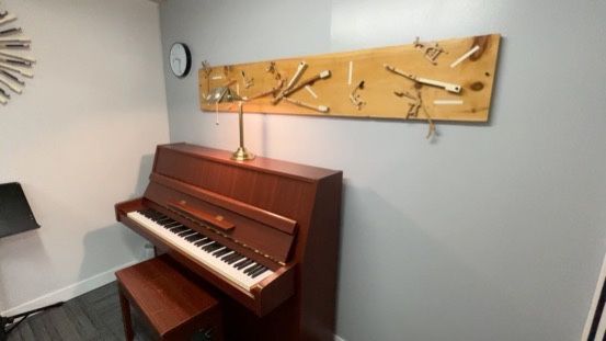 A piano is sitting in a room with a clock on the wall.