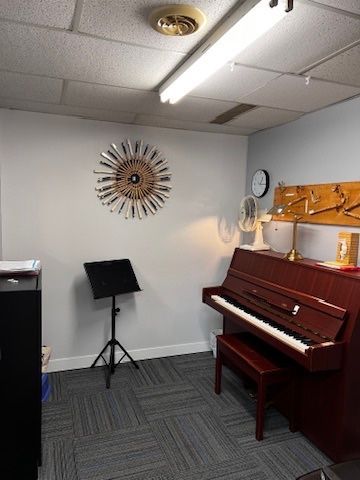 A room with a piano and a clock on the wall.
