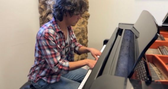 A man in a plaid shirt is playing a piano.