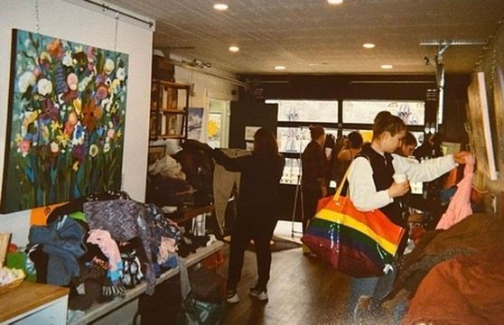 A group of people are standing in a room looking at clothes