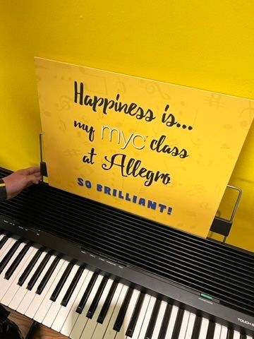 A person is holding a sign on top of a piano keyboard.
