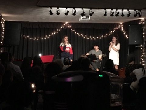 A group of people standing on a stage with a man playing a guitar