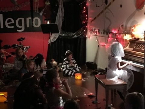 A group of children are sitting around a piano in a room.
