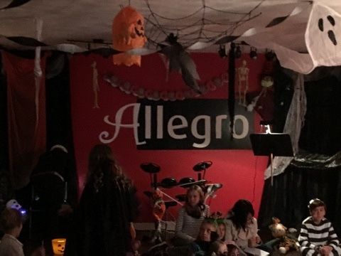 A group of people are gathered in front of a sign that says allegro