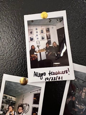 A polaroid picture of allegro teachers is pinned to a black wall