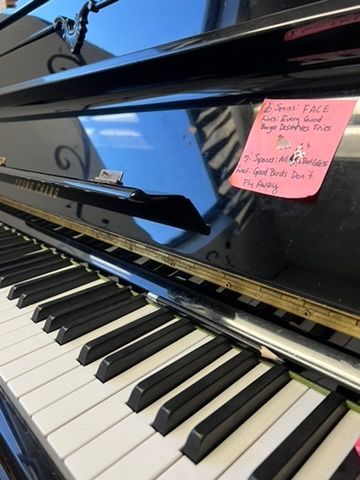 A close up of a piano with a sticky note on it.