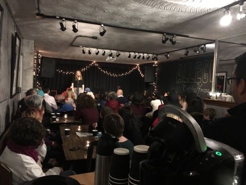 A group of people are sitting in a room watching a performance.