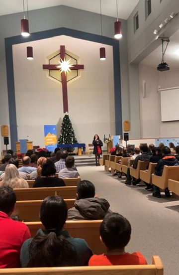 A group of people are sitting in a church with a cross in the background