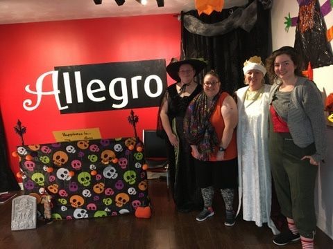 A group of women are posing for a picture in front of a sign that says allegro.