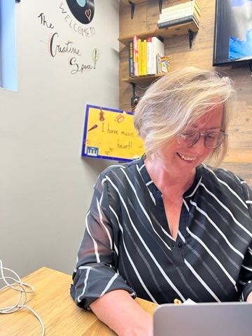 A woman is sitting at a table using a laptop computer.