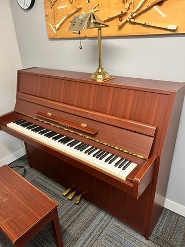 A piano is sitting in a room with a clock on the wall.