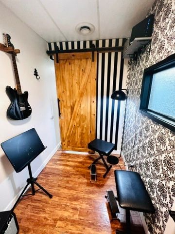 A room with a guitar hanging on the wall and a sliding barn door.