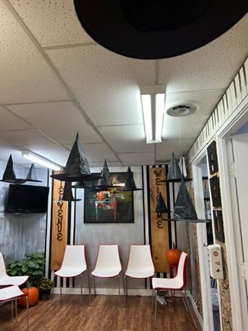A waiting room decorated for halloween with witch hats hanging from the ceiling.