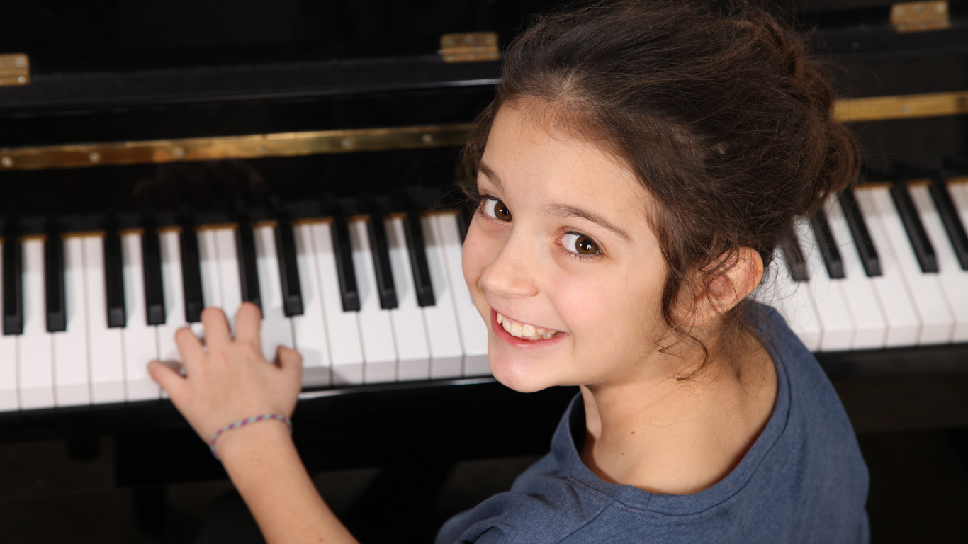 Smiling child playing a piano keyboard with one hand
