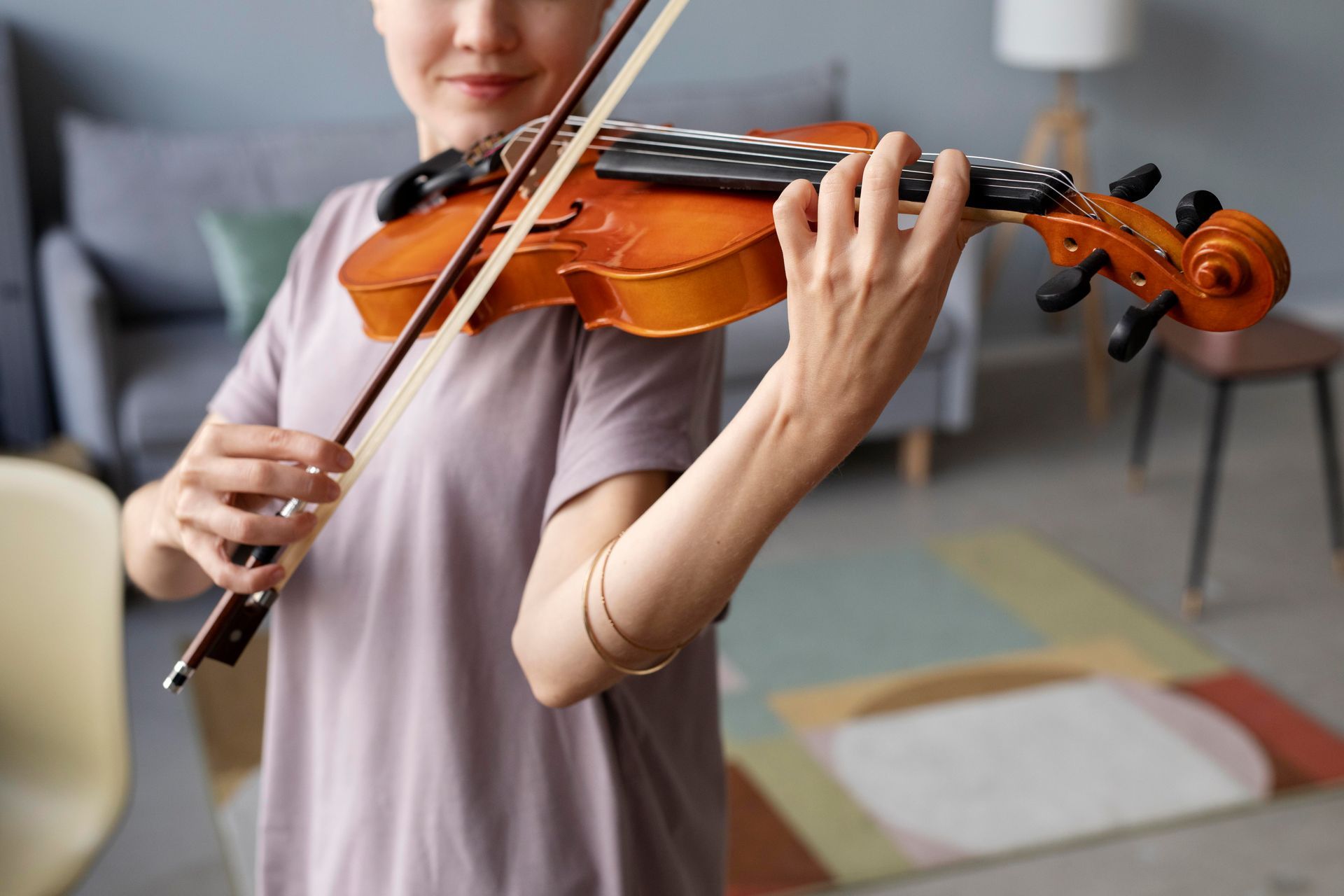 A woman is playing a violin in a living room.
