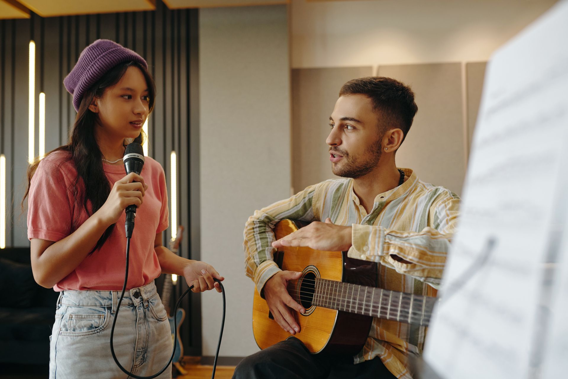 A man is playing a guitar and a woman is singing into a microphone.