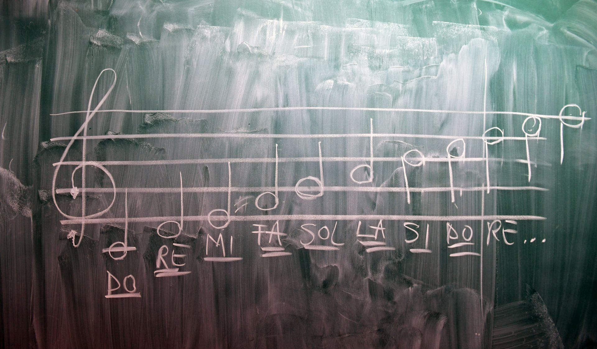 Musical staff and notes drawn on a chalkboard, labeled with solfège syllables.