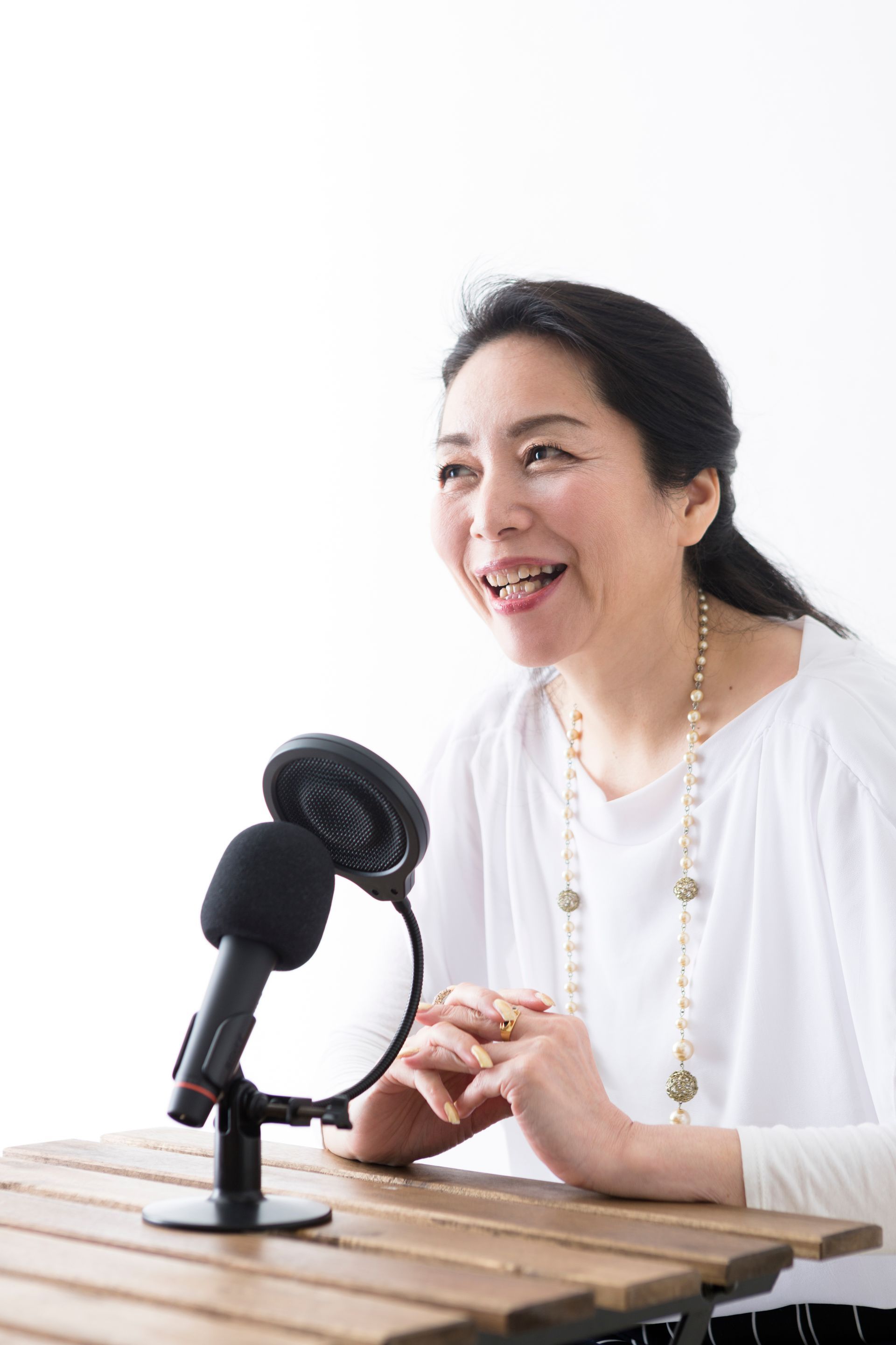 A woman is sitting at a table in front of a microphone.