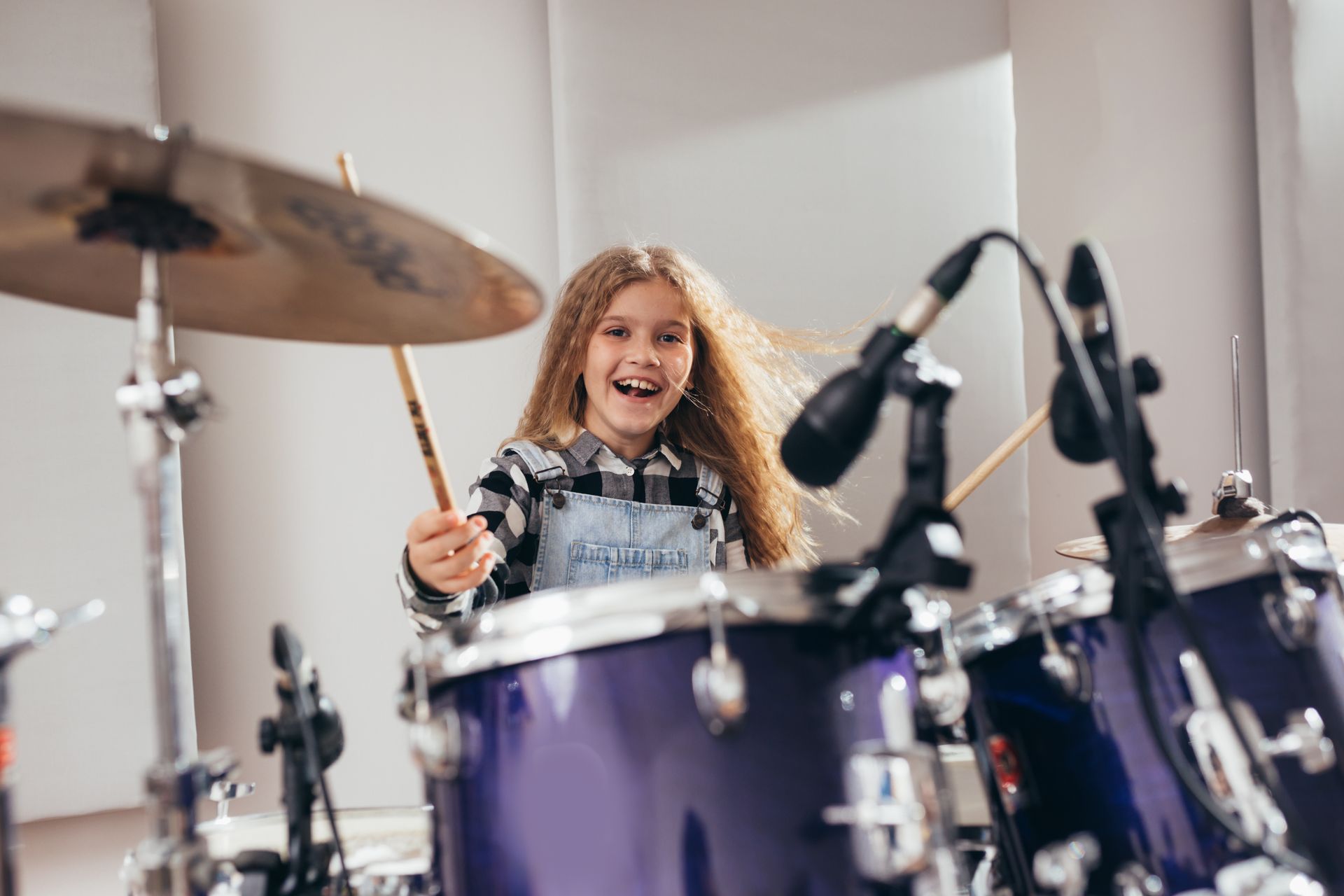 A young girl is playing drums in a room.