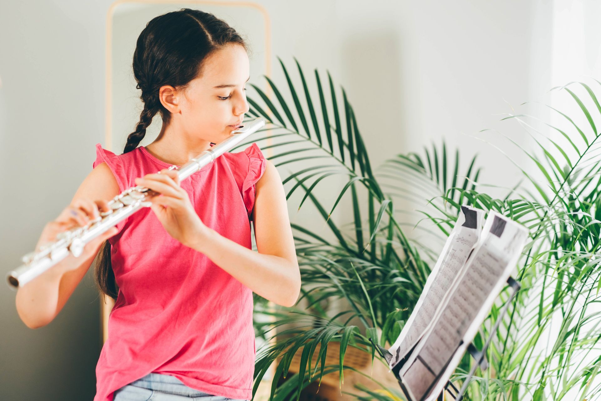 A young girl is playing a flute in a living room.