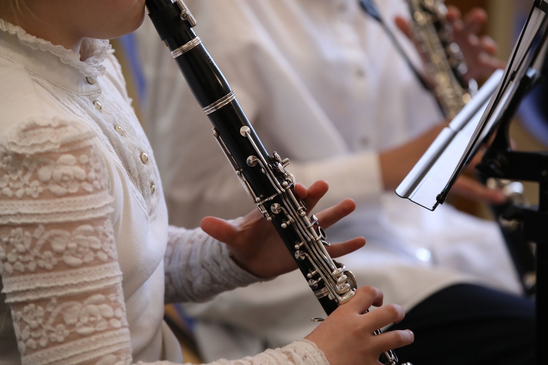 Person playing a clarinet in an orchestra, close-up on hands and instrument.