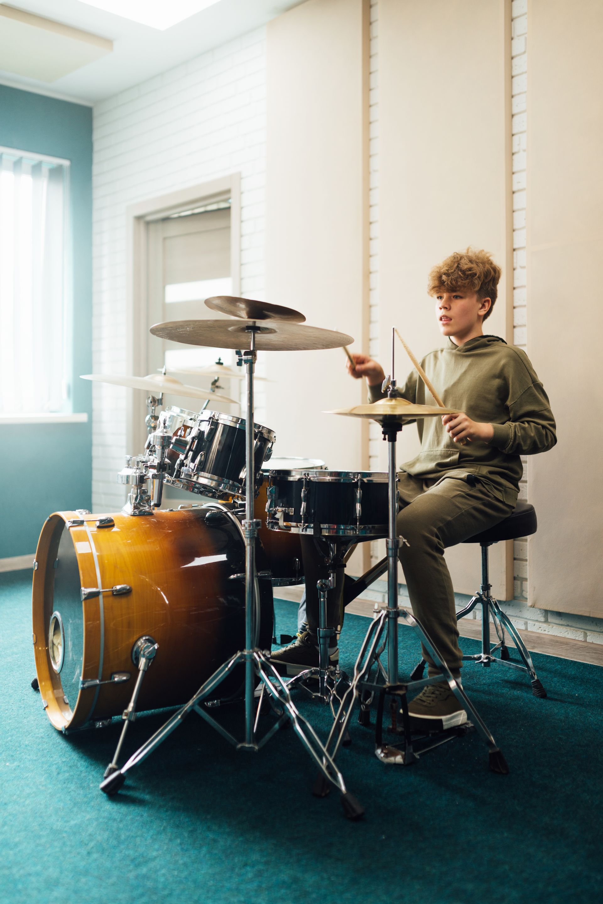 A young boy is playing drums in a room.