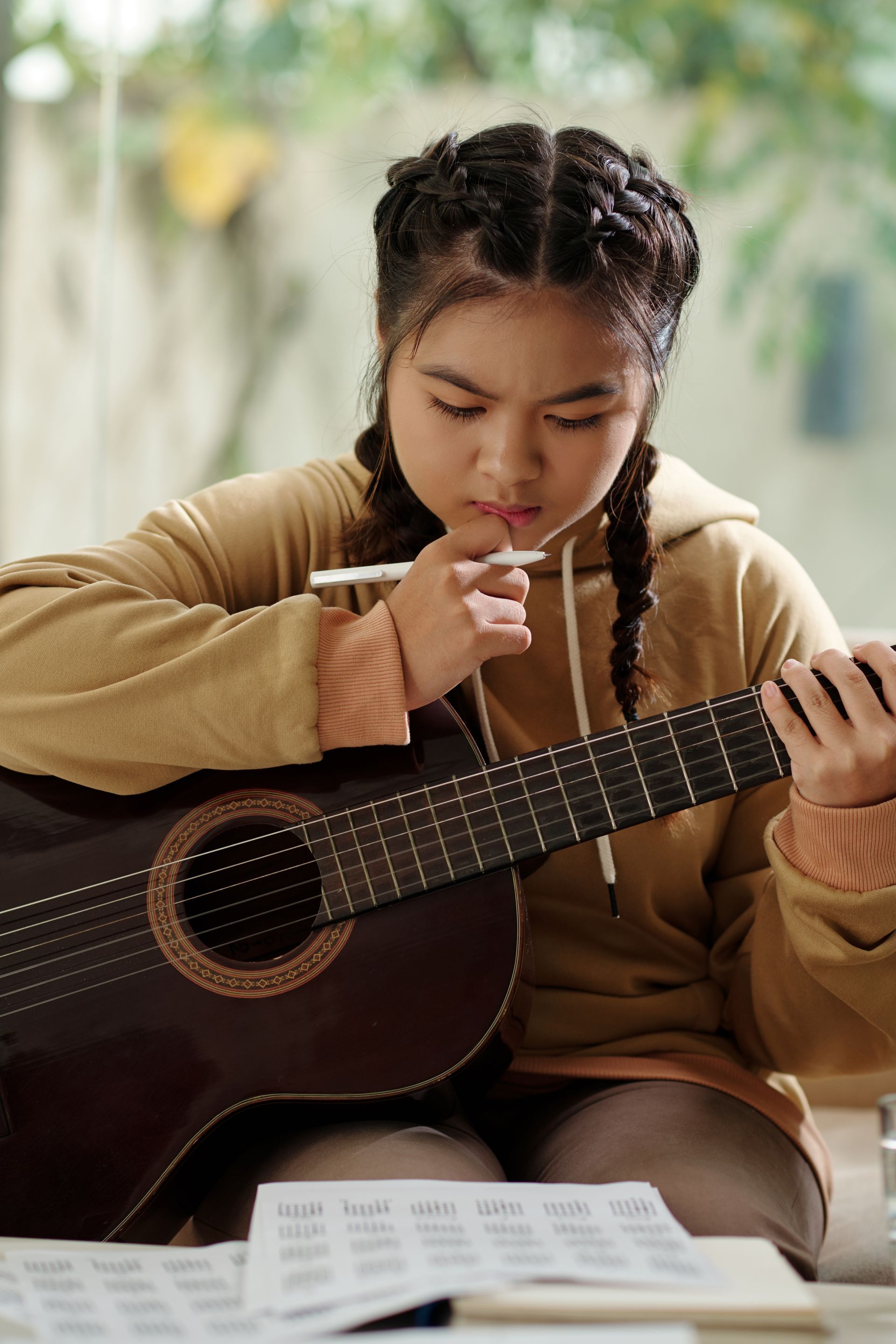A young girl is sitting at a table playing a guitar.