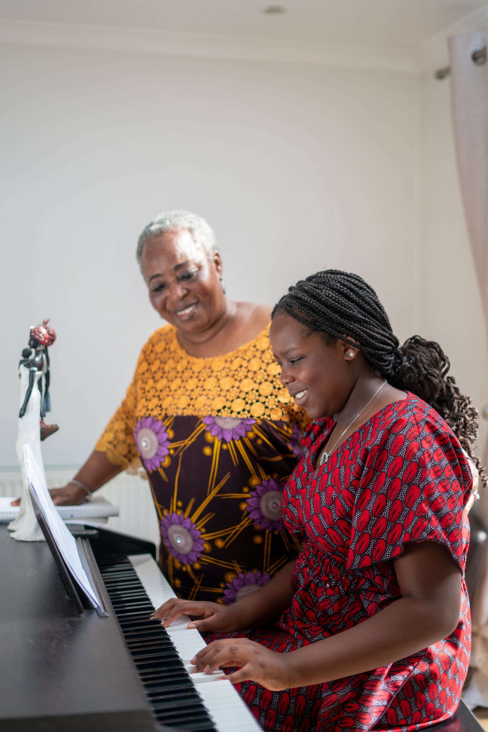 A woman is teaching a young girl how to play the piano.