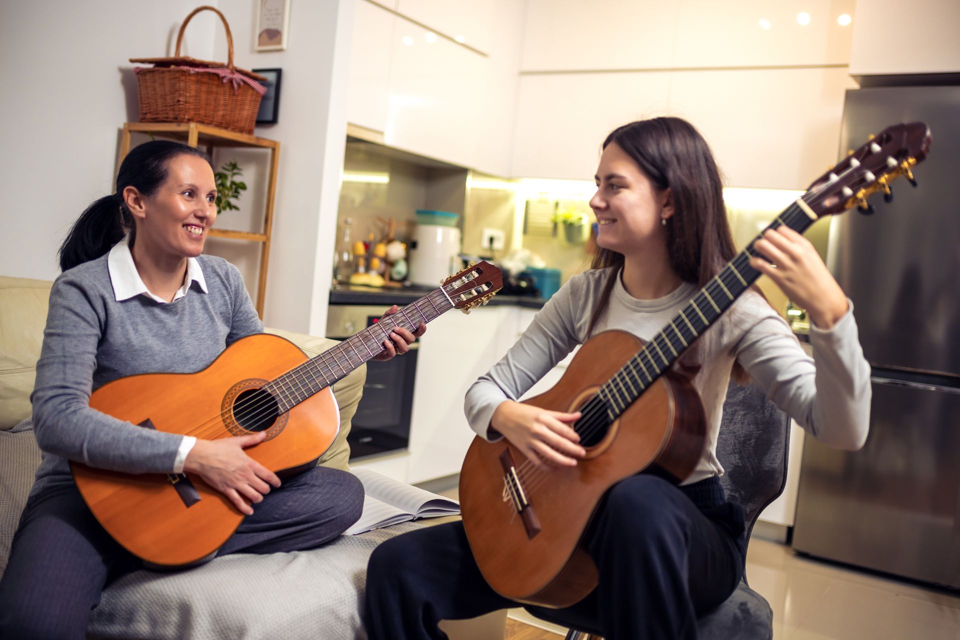Two women are playing guitars in a living room.