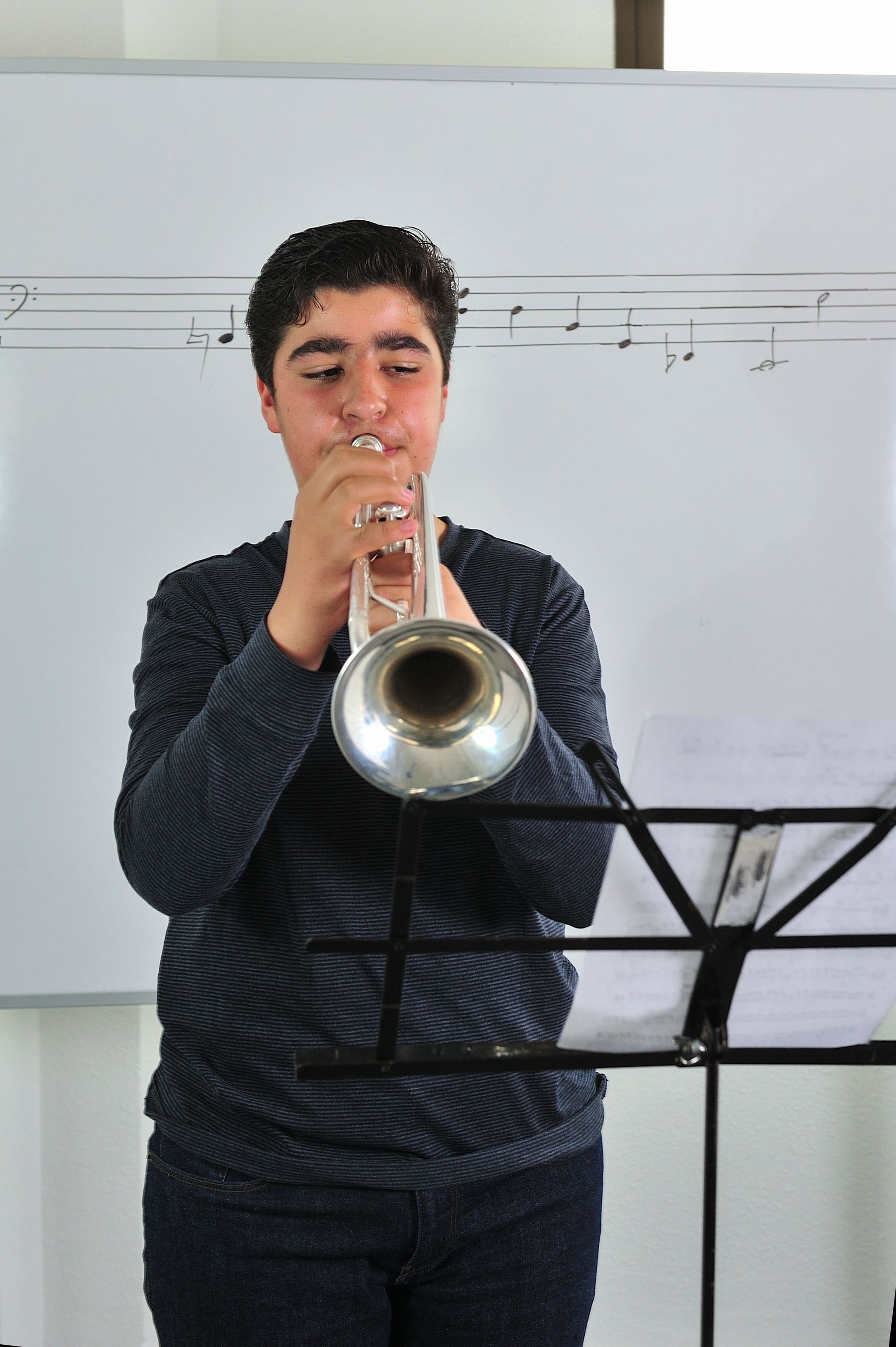 Person playing trumpet behind a music stand indoors