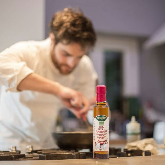 Chef professionista che irrora un piatto con olio Aromolio in cucina