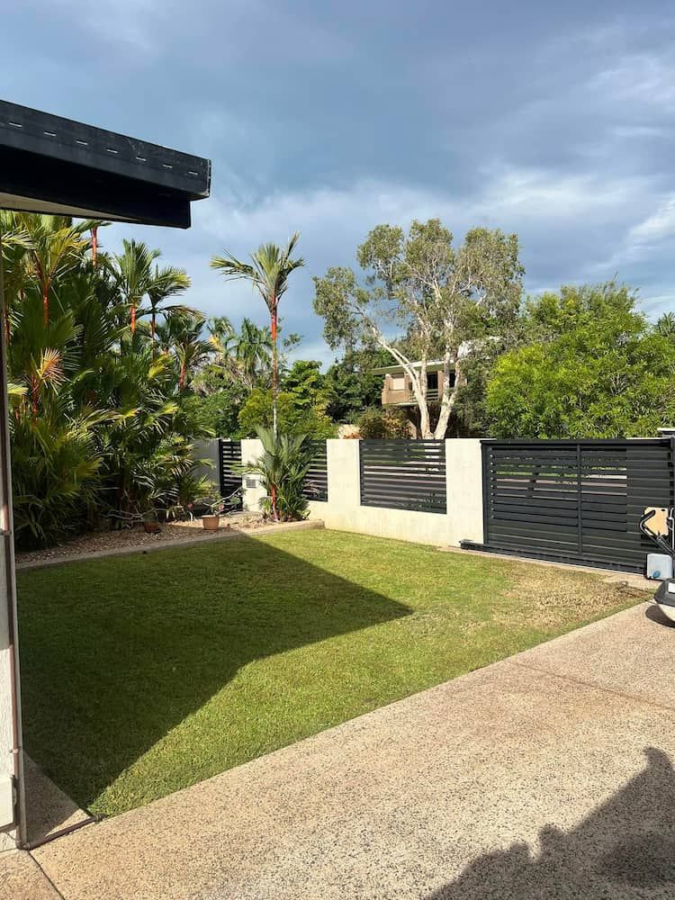 Lawn Next to a Building, With a Dark Fence and Trees Against a Cloudy Sky — Green Scene NT in Darwin, NT