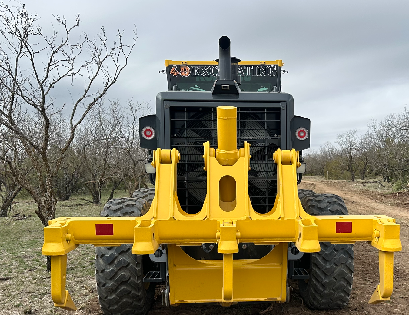 A yellow excavator is digging a hole for a pipe.