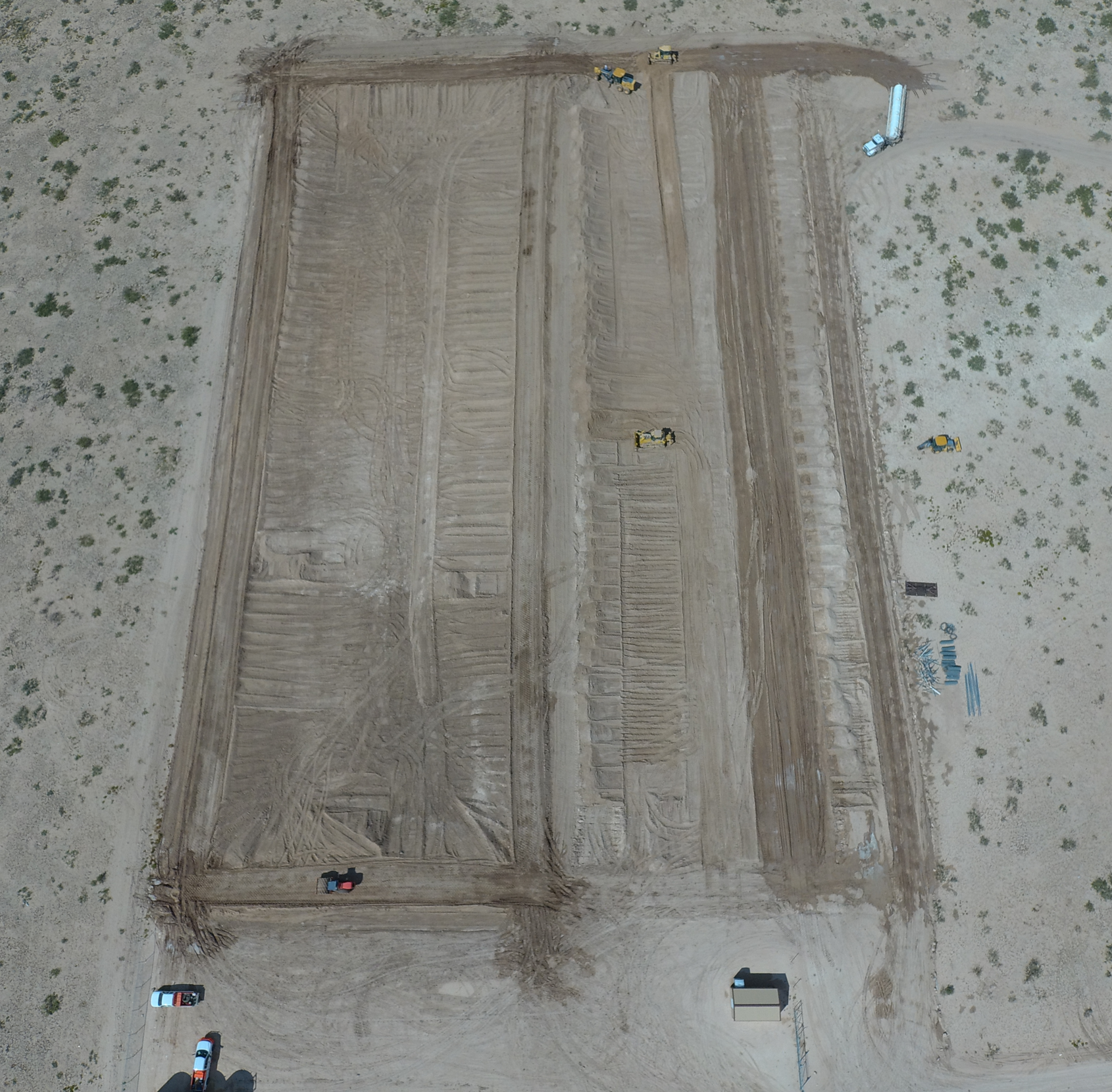 A bulldozer is moving dirt on a dirt road.