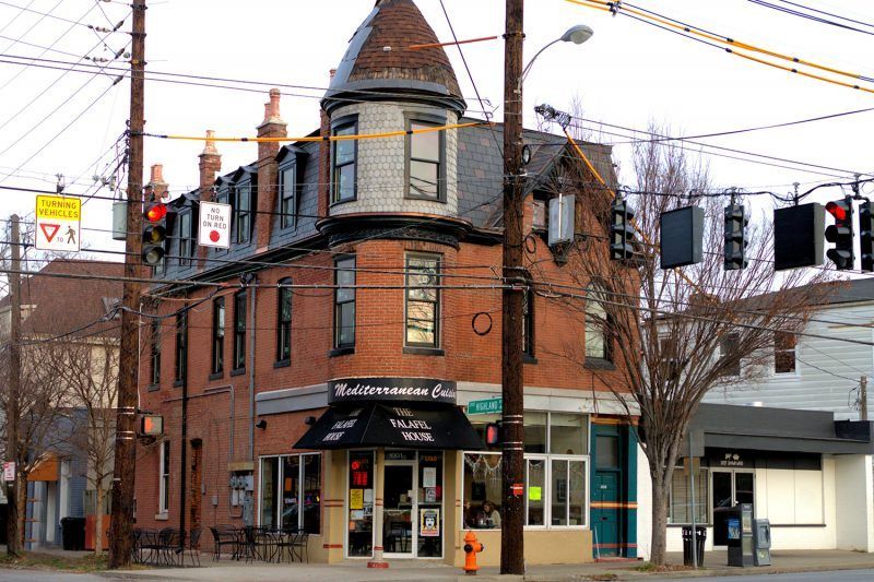 A brick building on the corner of a street with a fire hydrant in front of it