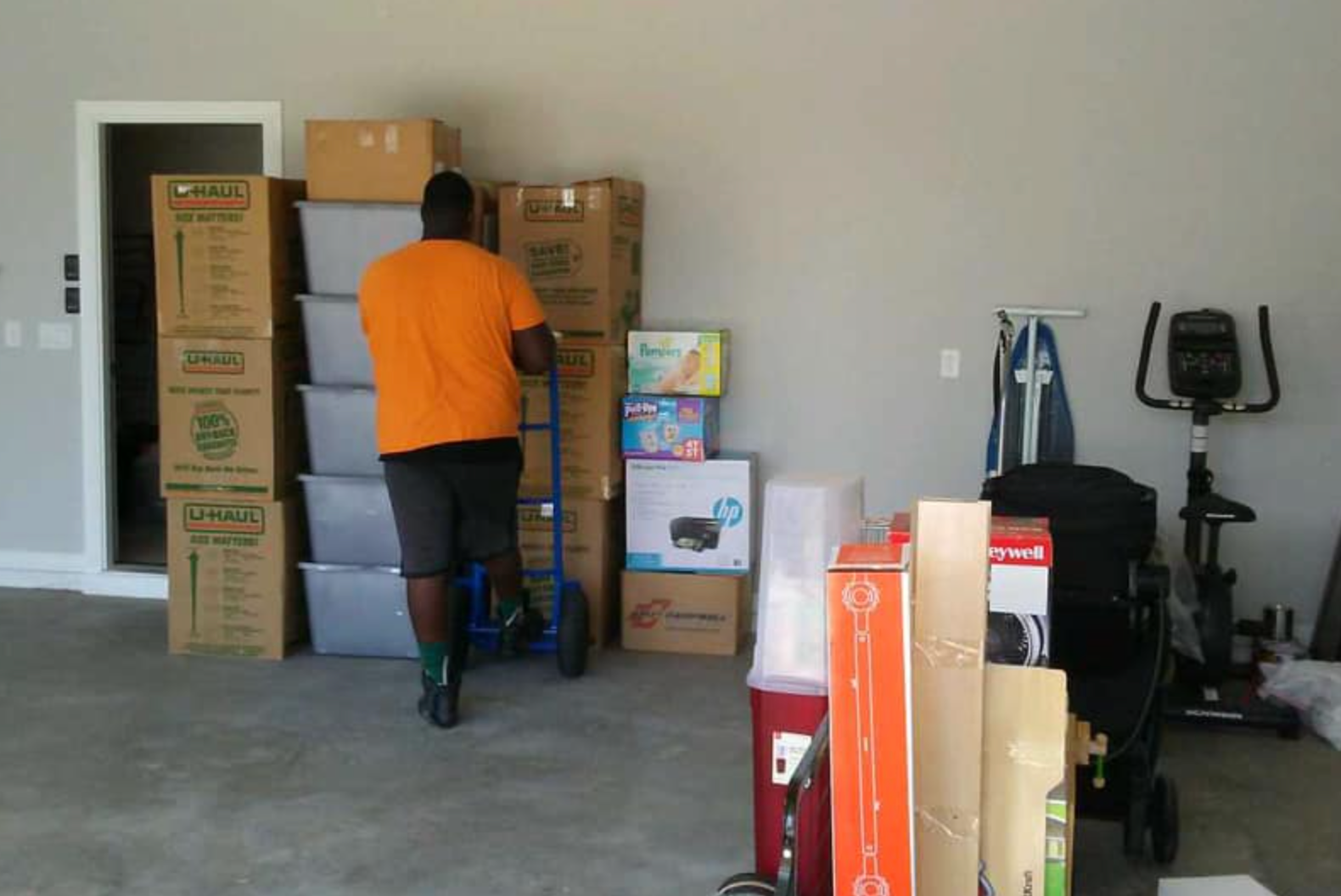 A man is pushing a cart full of boxes in a garage