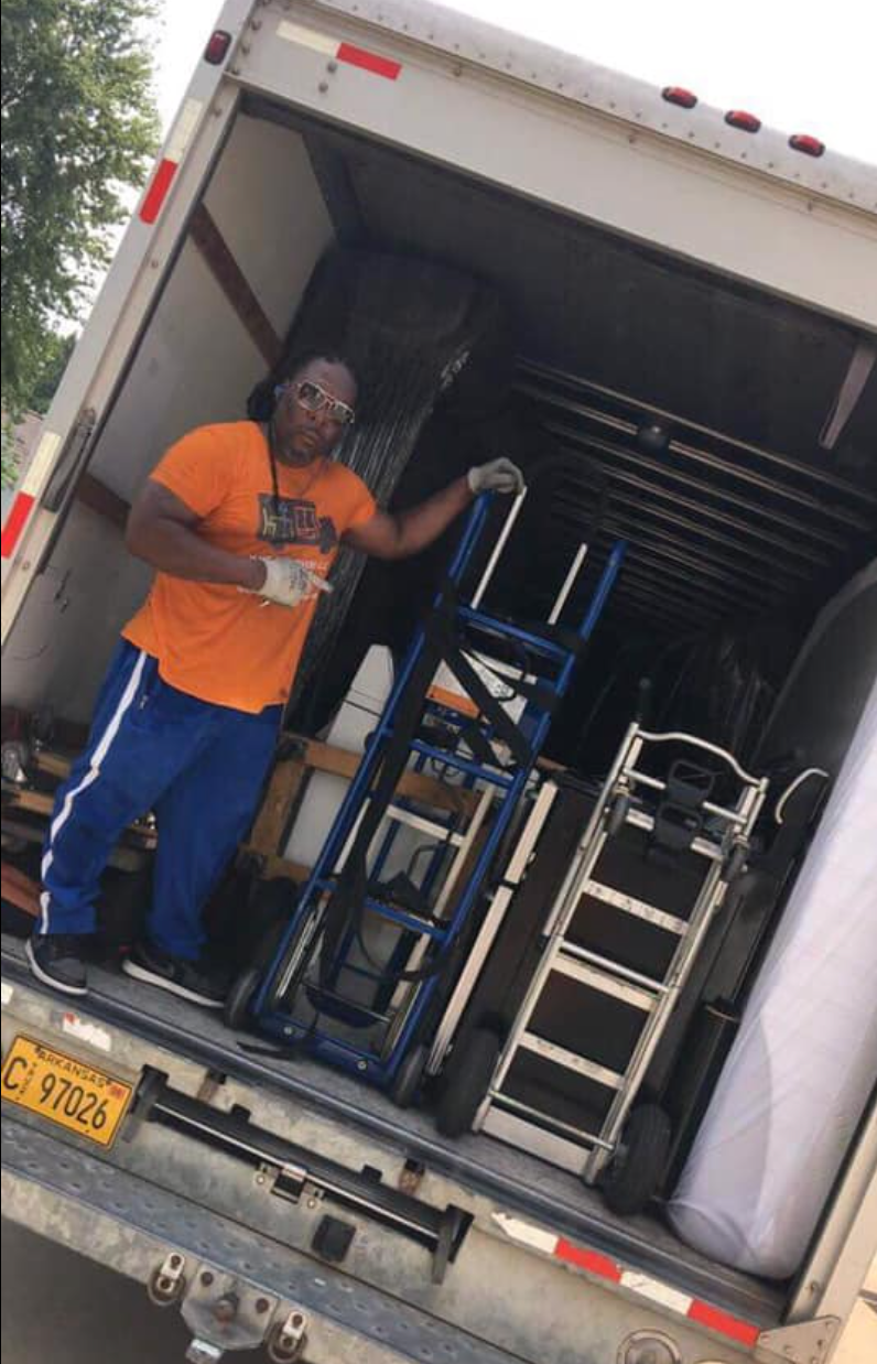 A man is standing in the back of a moving truck.