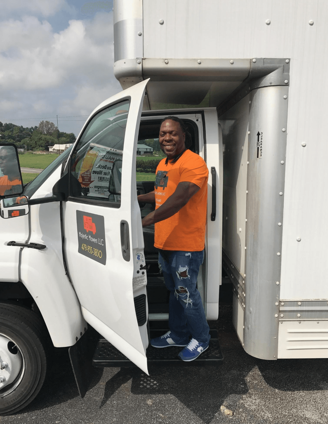 A man in an orange shirt is getting out of a white truck